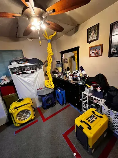 Dehumidifiers and air movers set up in a bedroom after a water leak