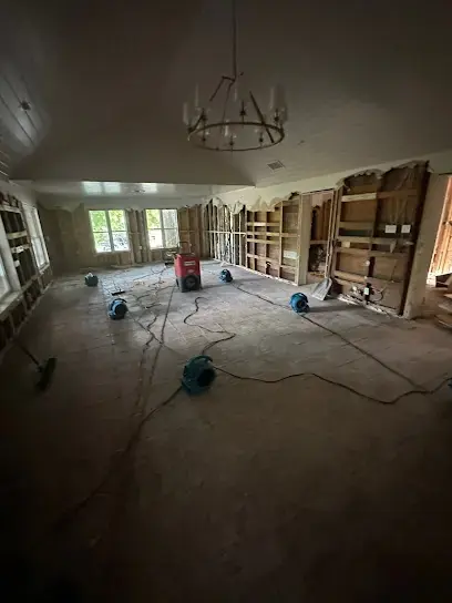Air movers drying a dark, emptied room after water damage in a Commerce City home