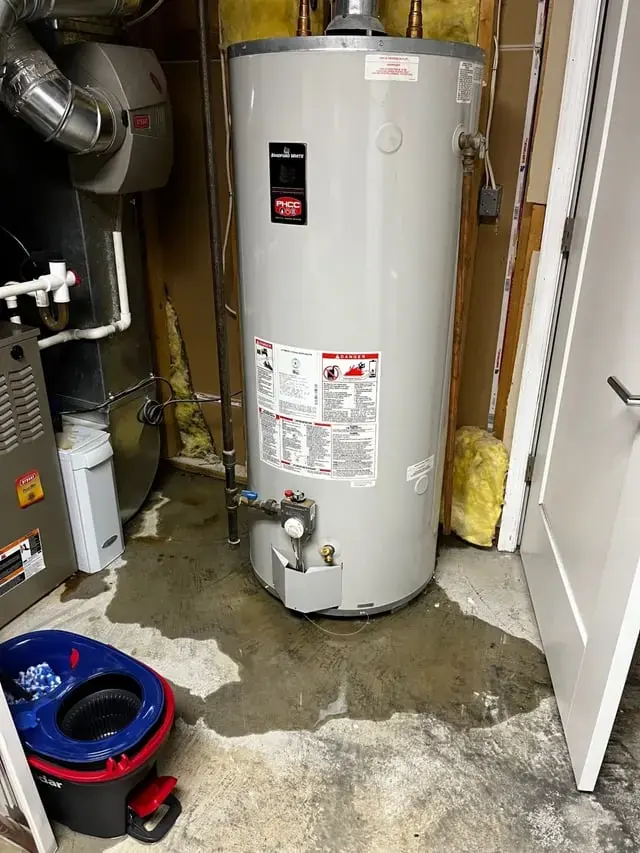 Water heater in a utility closet with water spread across the floor